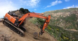 Excavator compacting slope along State Route 33